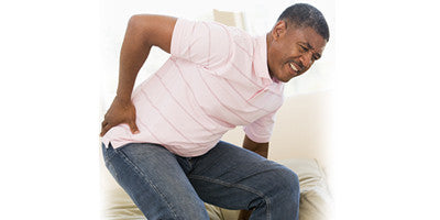 Person clutching their lower back in pain, illustrating common causes of back ache.