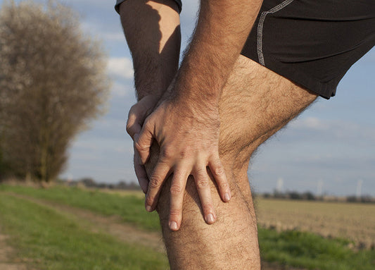Person holding their knee in discomfort, representing lingering joint and muscle pain