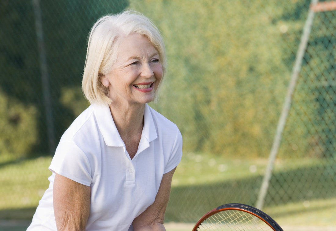 Person playing tennis outdoors, illustrating the sport's cardiovascular and strength benefits